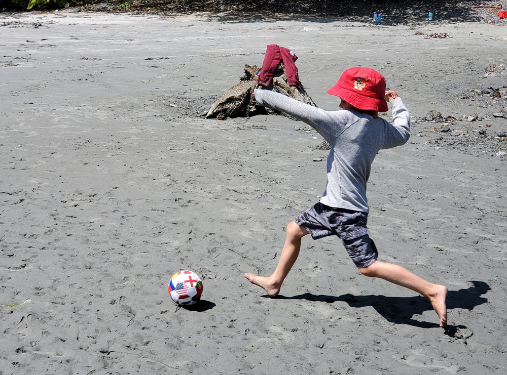 Boy playing with a soccer ball on the beach